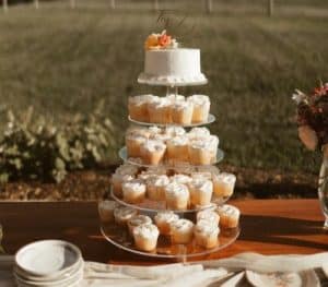 A tiered dessert display featuring a small white cake on top and multiple cupcakes decorated with frosting on lower tiers.