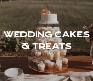 A tiered dessert display featuring a small white cake on top and multiple cupcakes decorated with frosting on lower tiers.