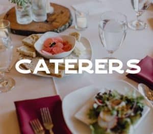 A dining table set with a plate of bread and a bowl of sliced vegetables, alongside a salad, water glasses, and decorative elements.