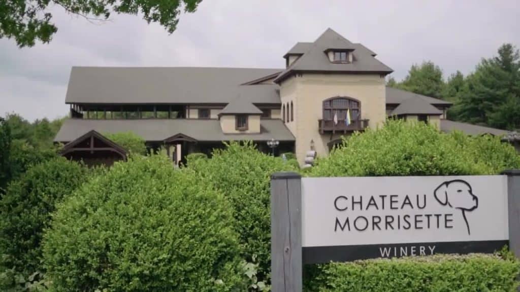 A building with a large, sloped roof and a sign that says "Chateau Morrisette Winery," surrounded by green bushes and trees.