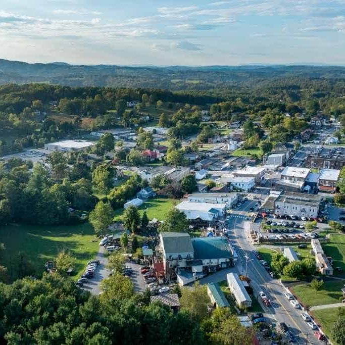 Aerial view of a small town surrounded by hills, featuring streets, buildings, and greenery.